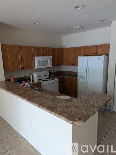 A kitchen with brown cabinets and a white fridge.