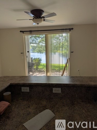 A room with a fan and a window overlooking a green area.