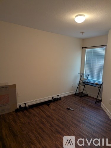 A room with wooden flooring and a window with blinds.