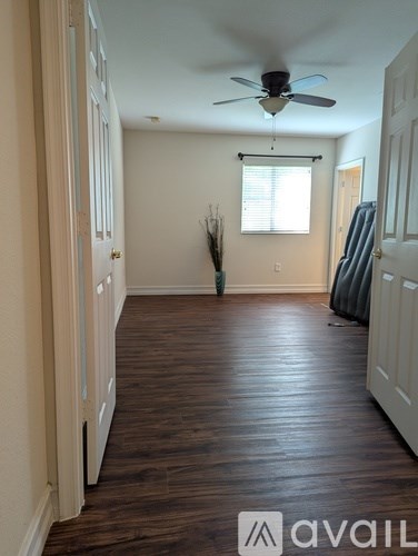 A room with a ceiling fan and wooden flooring.
