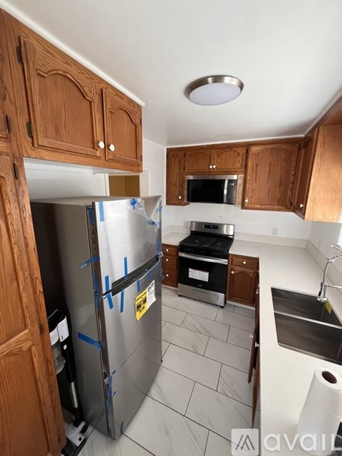A kitchen with wooden cabinets and a refrigerator covered in blue tape.