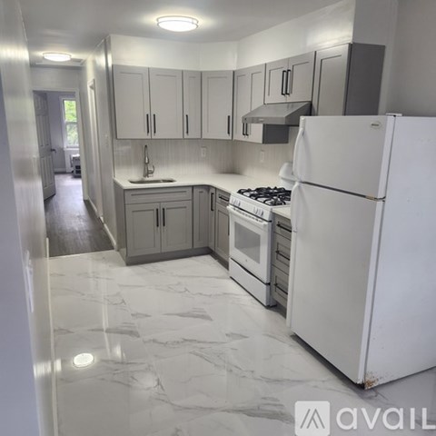A kitchen with a white fridge and a white marble floor.