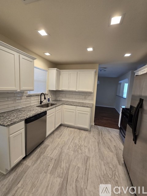 A kitchen with white cabinets and a granite countertop.