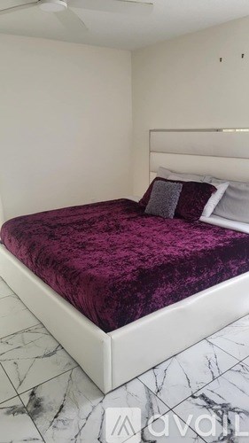 A bed with a purple bedspread is in the image.