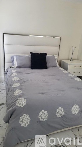 A bed with a grey comforter and a white headboard.