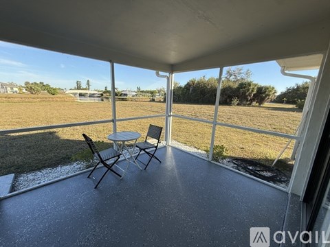 A patio with a table and chairs overlooking a grassy field.