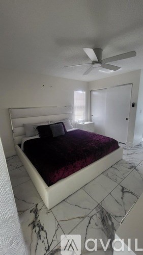 A bedroom with a bed, a ceiling fan, and a marble floor.