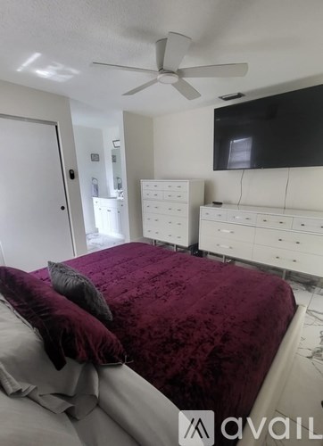 A bedroom with a bed, dresser, and ceiling fan.