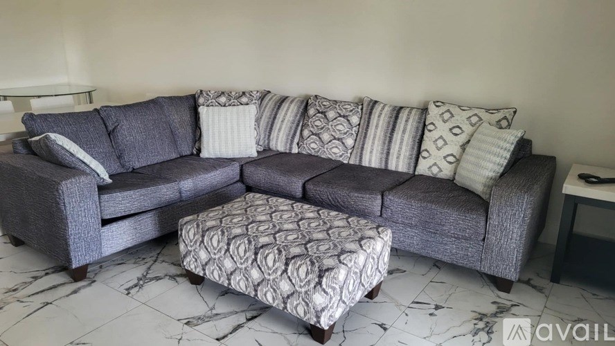 A grey couch with a patterned ottoman in front of it.