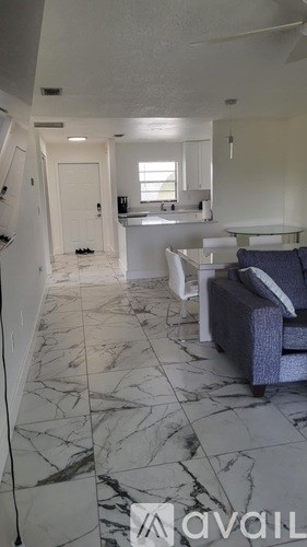 A living room with a grey couch and a marble floor.