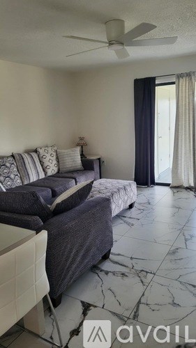 A living room with a grey couch and a marble floor.