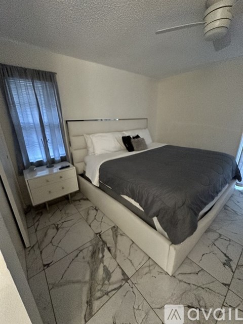 A bedroom with a bed, nightstand, and window with curtains.