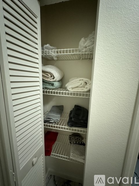 A white cabinet with a shelf and towels on it.