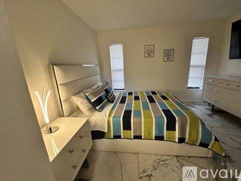 A bedroom with a bed, dresser, and window.