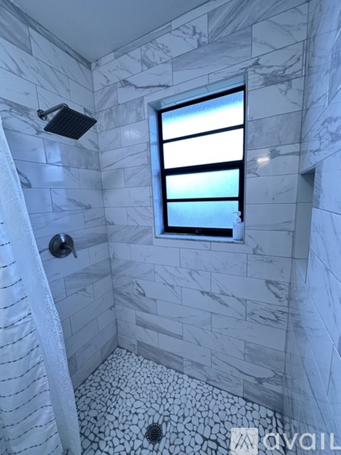 A bathroom with a marble wall and a window.