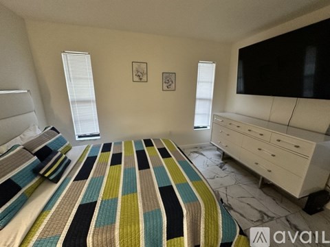 A bedroom with a bed, dresser, and television.