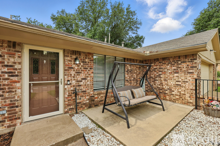A patio with a chair and a table is surrounded by a brick wall.