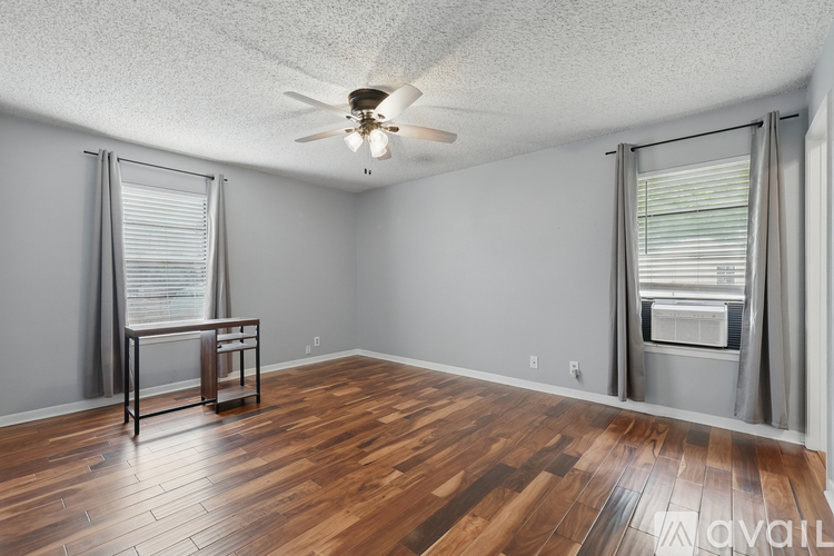 A room with wooden floors and a ceiling fan.