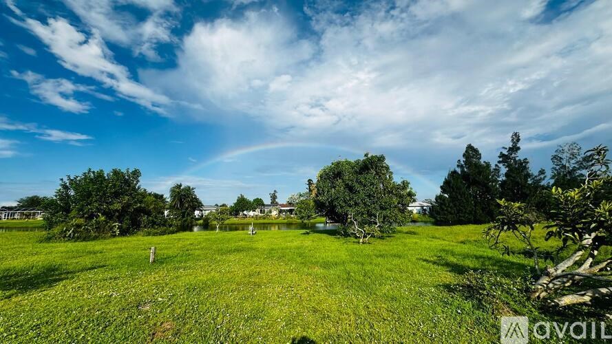 A grassy field with trees and a partly cloudy sky.