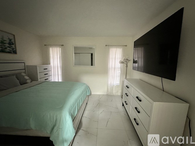 A bedroom with a bed, dresser, and television.