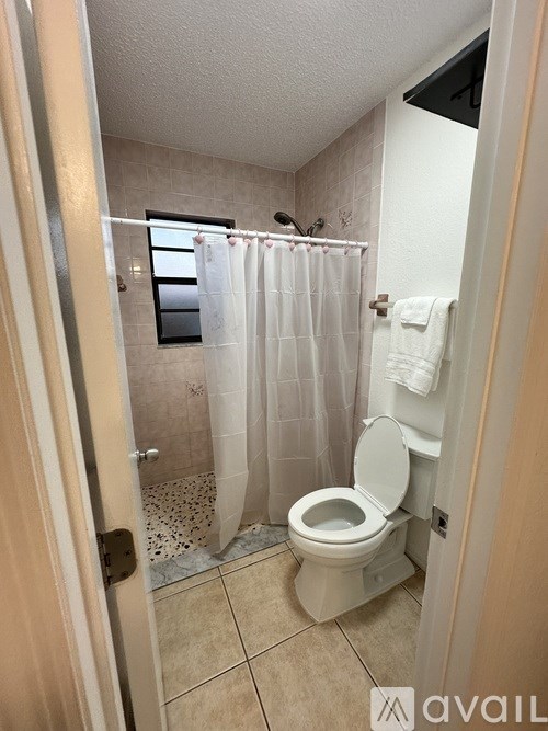 A bathroom with a toilet, shower curtain, and a towel rack.