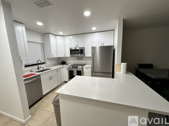A kitchen with white cabinets and appliances is available for rent.
