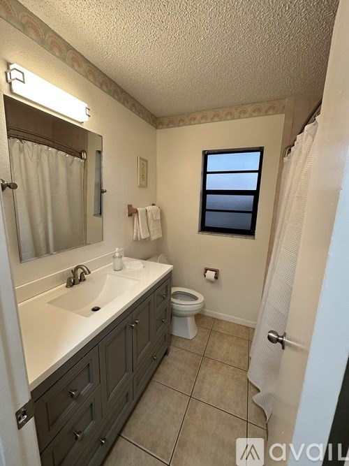 A bathroom with a toilet, sink, and mirror.