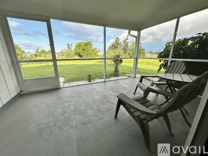 A patio with a table and chairs overlooking a green lawn.