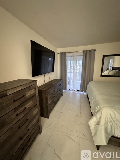 A bedroom with a bed, a dresser, and a television.