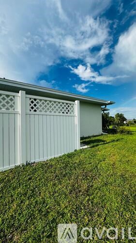 A white building with lattice windows sits in a grassy field.