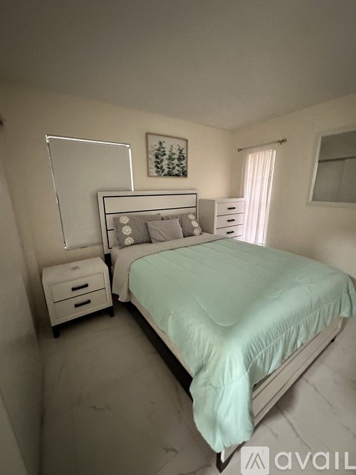 A bedroom with a bed, nightstands, and a picture on the wall.