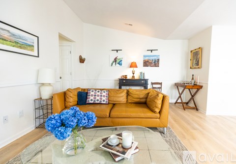 A living room with a yellow couch and a coffee table with a vase of blue flowers on it.