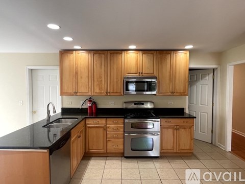 A kitchen with wooden cabinets and black countertops.