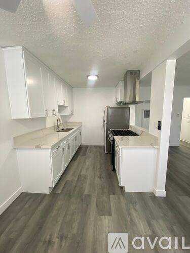 A kitchen with white cabinets and a grey floor.