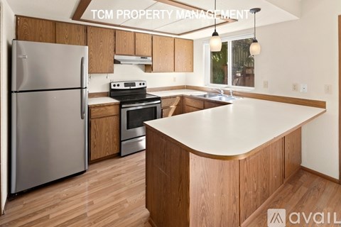 A kitchen with wooden cabinets and a stainless steel refrigerator.