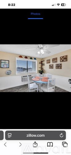 A dining room with a table set for two and a view of the outdoors through the window.