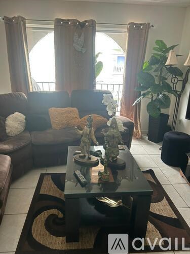A living room with a glass coffee table and a brown couch.