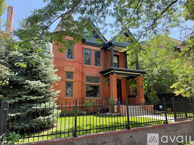 A large house with a tower and a gate in front.
