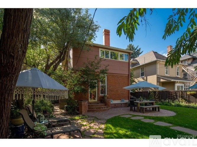 A backyard with a patio, a table and chairs, and a tree.