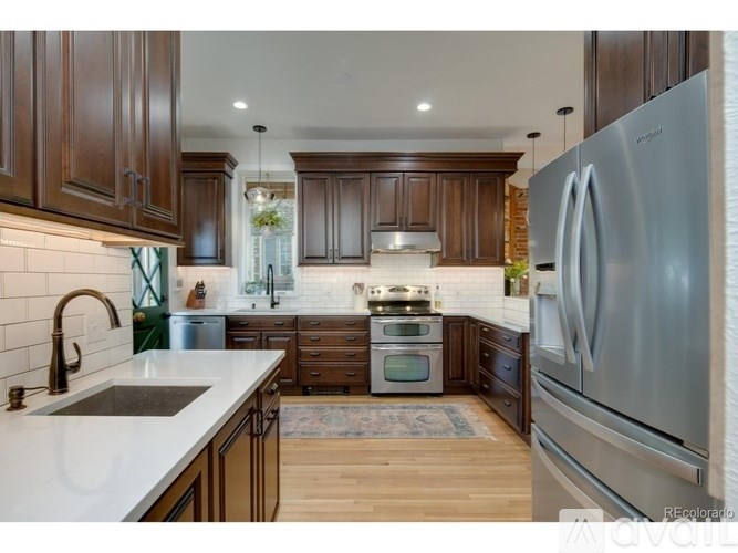 A backyard with a lawn, a tree, and a bench.