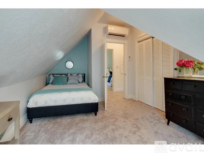 A bedroom with a bed, dresser, and a window with blinds.