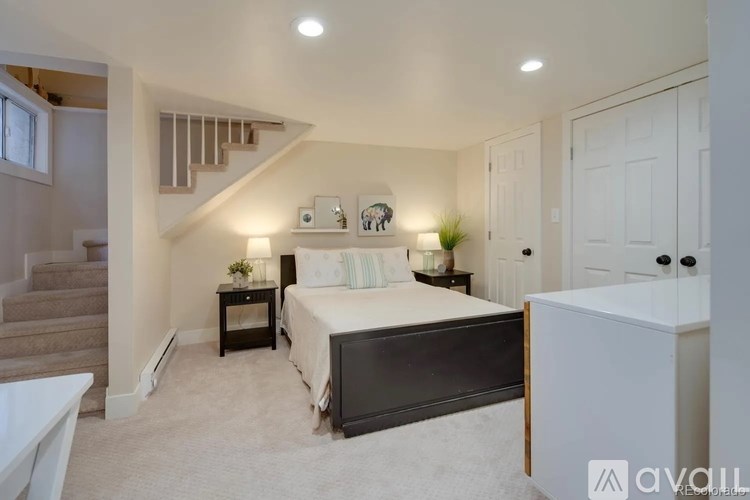 A bedroom with a large bed, a staircase, and a white cabinet.