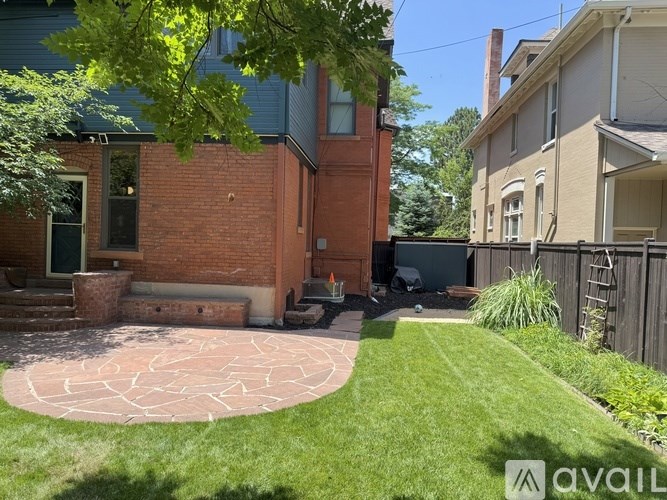 A backyard with a brick patio and a green lawn.
