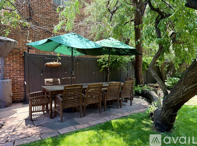A patio with a table and chairs under a green umbrella.