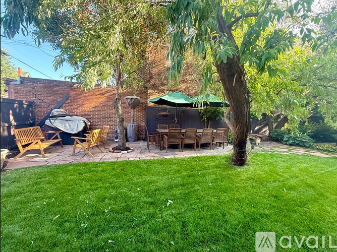 A backyard with a tree, chairs, and a fire pit.