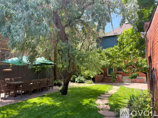 A backyard with a table and chairs under a tree.