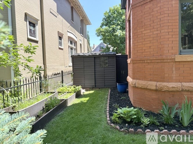A backyard with a fence, a small garden, and a brick building.
