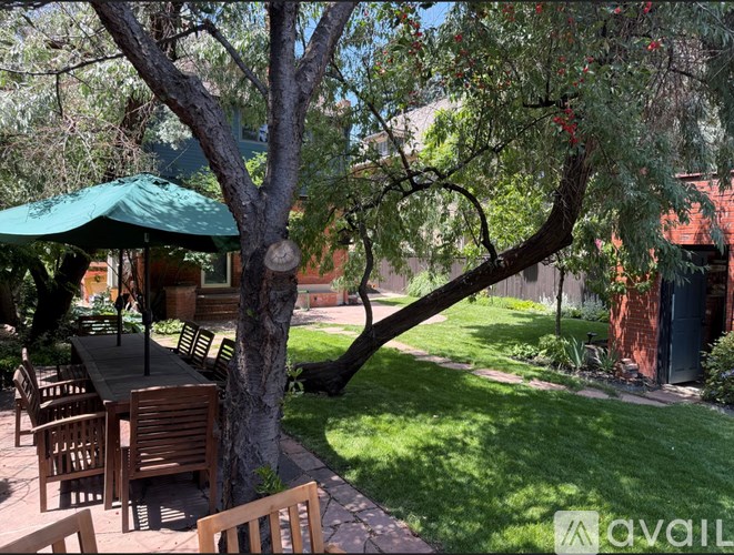 A patio with a table and chairs under a tree.