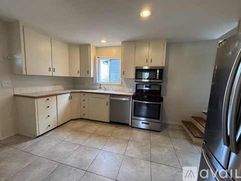 A kitchen with white cabinets and a stainless steel refrigerator.