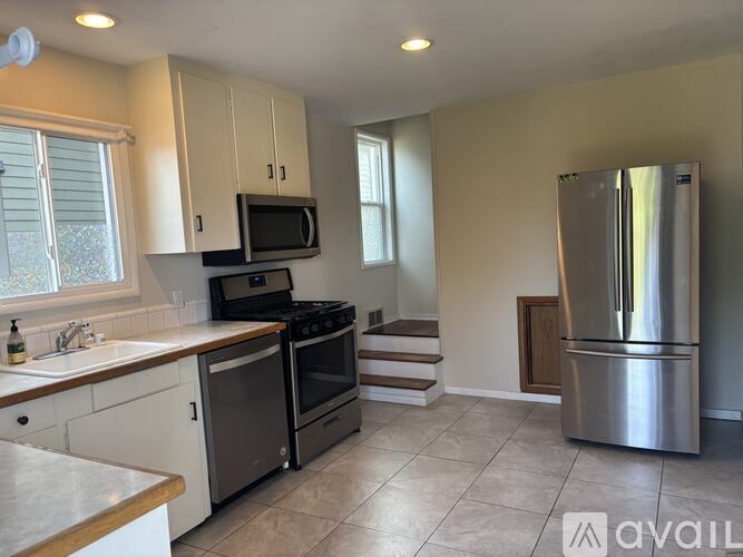 A kitchen with a stainless steel refrigerator and a microwave above the stove.
